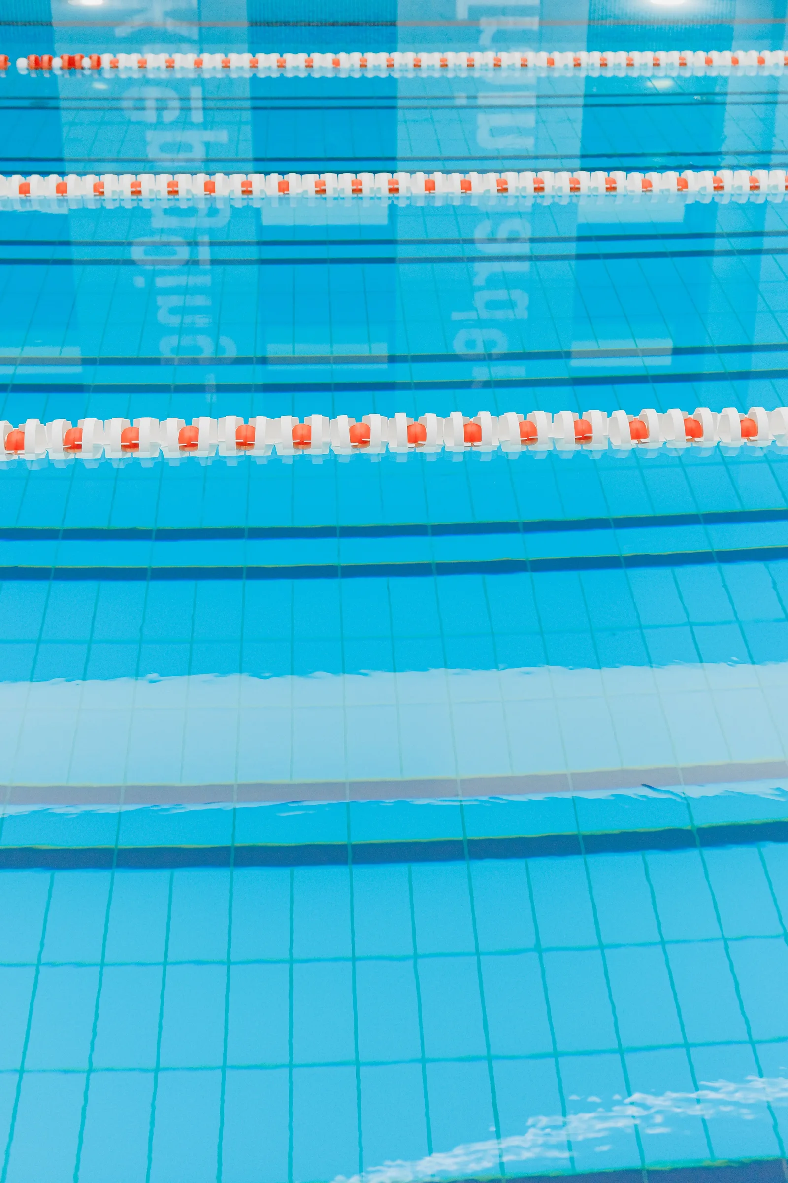 Clear blue swimming pool water with floor markings visible beneath lane dividers