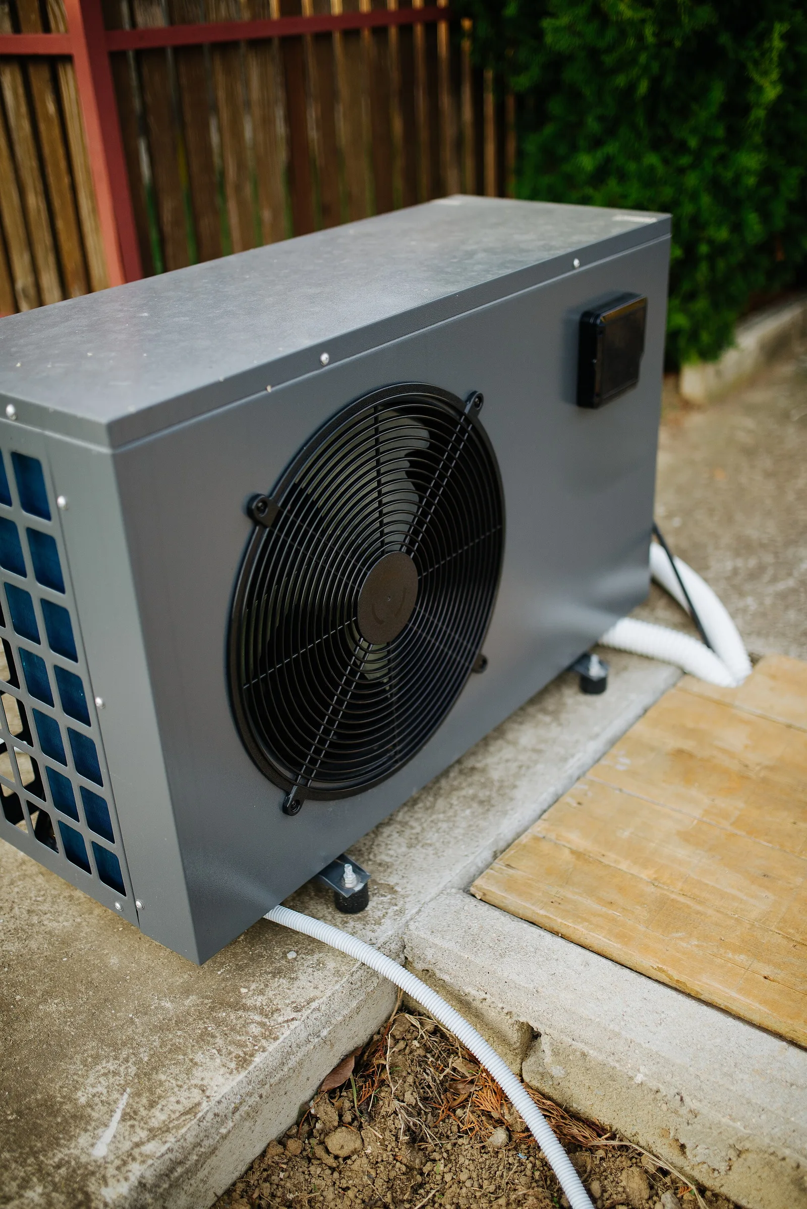 Outdoor pool heat-pump cabinet with a large fan and connected plumbing