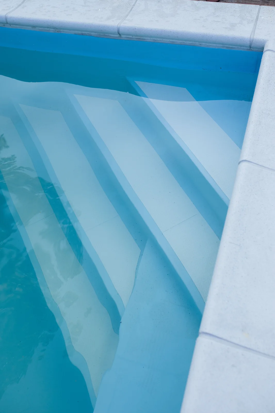 Clear blue swimming pool water over clean white entry steps